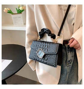 Détail du sac noir à motif crocodile avec poignée nuage et boucle sur le mannequin