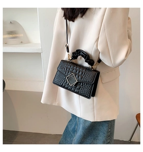 Détail du sac noir à motif crocodile avec fermoir métallique et poignée froncée chic