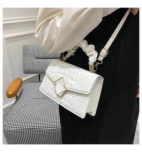 Détail du sac à main blanc motif crocodile avec boucle dorée et anse style chouchou