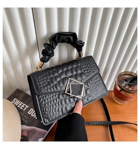 Détail du sac à main noir texture croco avec fermoir doré et poignée froncée