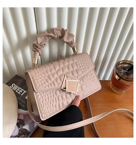 Détail du sac beige effet crocodile avec fermoir doré et poignée froncée élégante