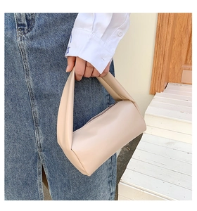 Detail view of a cream leather mini top handle bag with a smooth pillow shape and zipper