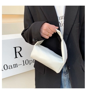 Close-up of minimalist white soft leather handbag with integrated handle for spring fashion