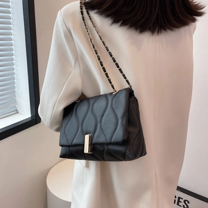 Sac bandoulière noir chic avec matelassage ondulé, chaîne dorée et fermoir métal