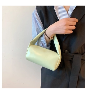 Close-up of a pale green leather handbag held by a model wearing a striped shirt