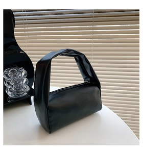 Detail of soft black PU leather handbag with wide pleated handle and top zipper closure