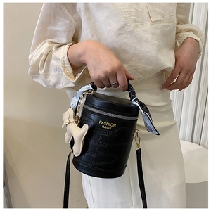 Detail of black crocodile pattern bucket bag with printed silk scarf handle and dog charm