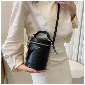 Detail of black crocodile texture bucket bag with silk scarf handle and heart charm