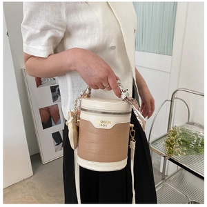 Close-up of beige and brown bucket bag with crocodile texture and silk scarf handle