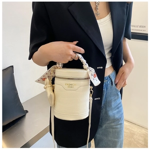 Detail of crocodile embossed cream bucket bag with silk scarf handle and gold hardware
