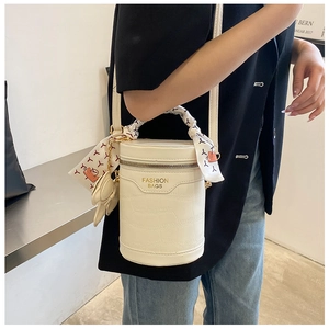Detail of white crocodile texture bucket bag with silk scarf handle and bear charm decoration