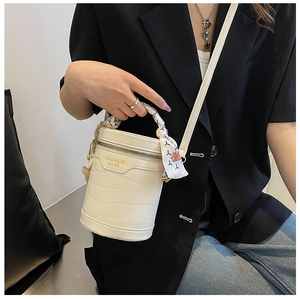 White bucket bag with crocodile texture and scarf-wrapped handle on a model