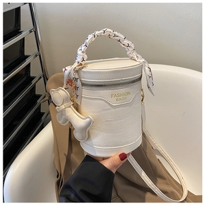 Close-up of white crocodile pattern bucket bag with silk scarf handle and bear charm