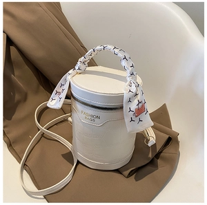 Close-up of white crocodile pattern bucket bag with printed silk scarf on handle