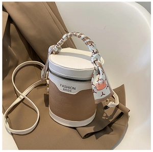 Detail of color-block bucket bag with crocodile texture and silk scarf handle decor