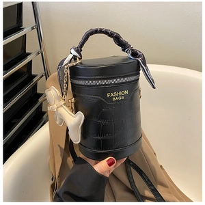 Detail of black crocodile texture bucket bag with silk-wrapped handles and bone charm
