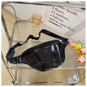 Detail of transparent black PVC waist bag with adjustable strap on a modern glass cart