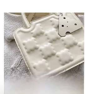 Detail shot of cream white handbag featuring waffle-textured fabric and scalloped edges