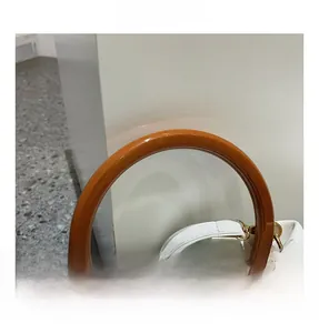 Close-up of cloud pleated white leather bag with orange resin handle and gold buckles