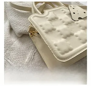 Macro view of creamy white biscuit bag showing scalloped edges and gold metal hardware details