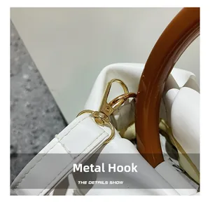 Close-up of golden hardware swivel hook and amber resin handle on white pleated cloud bag