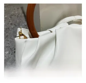 Detailed close-up of white ruched PU leather handbag with amber-textured round handle