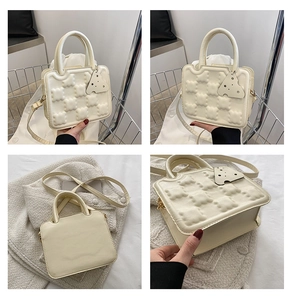 Close-up of cream square bag with 3D bubble texture and cute cheese pendant detail