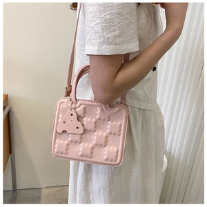Pink biscuit-patterned crossbody bag with cheese pendant shown in fashion street style