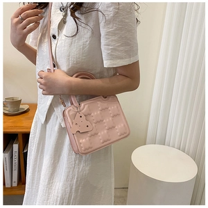 Close-up of pink cookie-patterned square bag with a cute cheese-shaped charm accessory