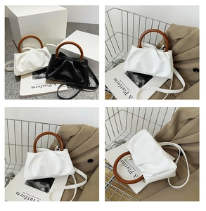 Detail of the pleated dumpling bag featuring a round wooden handle and leather texture