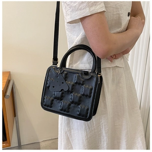 Detail of creative black biscuit shaped crossbody bag with textured PU leather finish