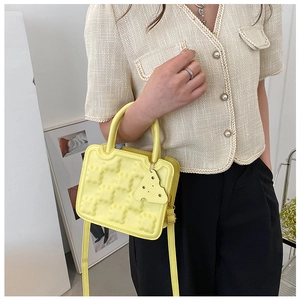 Close-up of a yellow biscuit-textured handbag with a cute cheese-shaped charm