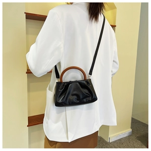 Chic black pleated cloud bag with vintage wooden handle worn over a white blazer
