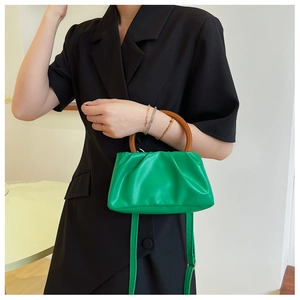Detail of green ruched cloud bag with brown circular handle and smooth leather finish