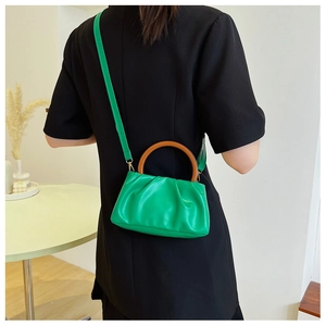 Detail of emerald green pleated cloud bag with a dark brown round wooden handle