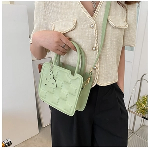 Detail of mint green quilted biscuit bag with cheese pendant and metal buckle strap