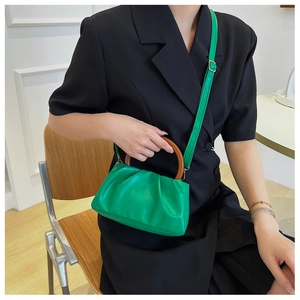 Detail of bright green ruched cloud bag featuring vintage dark wooden circular handles