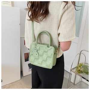 Pale green crossbody bag featuring embossed bear pattern and matching bear charm
