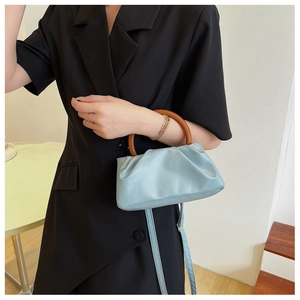 Close-up of mint blue cloud bag with pleated texture and brown circular resin handle