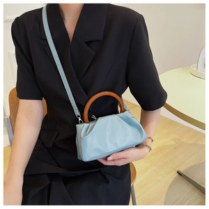 Detail of light blue pleated handbag featuring a distinctive round brown wooden handle
