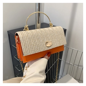 Detail showing orange leather and woven straw texture with gold metal handle and chain