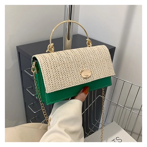 Detail of woven straw flap and gold metal handle on a green crossbody chain bag