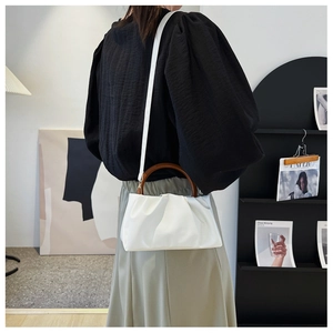 Detailed back view of a white ruched cloud bag featuring a brown resin ring handle