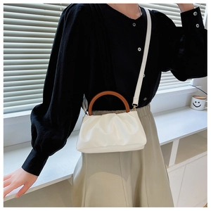 White pleated cloud bag with wooden round handle and sleek crossbody strap detail