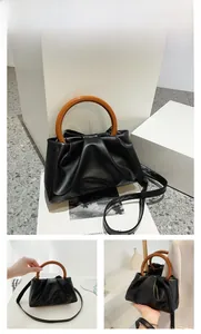 Detail of black cloud pleated bag with wooden ring handle and detachable strap