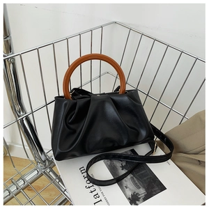 Detail of black pleated cloud handbag with resin handle and leather texture finish