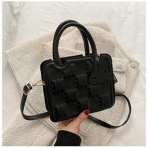 Detailed view of black biscuit textured handbag with embossed pattern and gold hardware