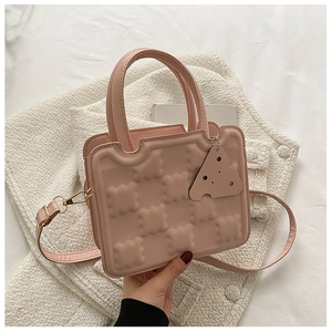 Detail of pink biscuit-shaped crossbody bag with waffle texture and cheese pendant