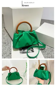 Detail of green ruched cloud bag featuring vintage wooden handle and glossy PU leather