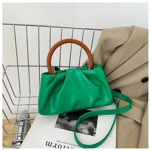 Detail of vibrant green cloud bag featuring a unique brown wood-textured ring handle